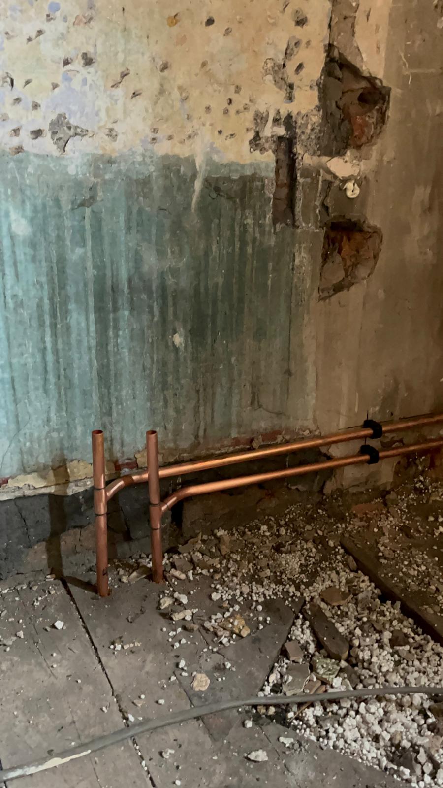 First fix copper heating pipework run along a stripped wall during a full central heating installation