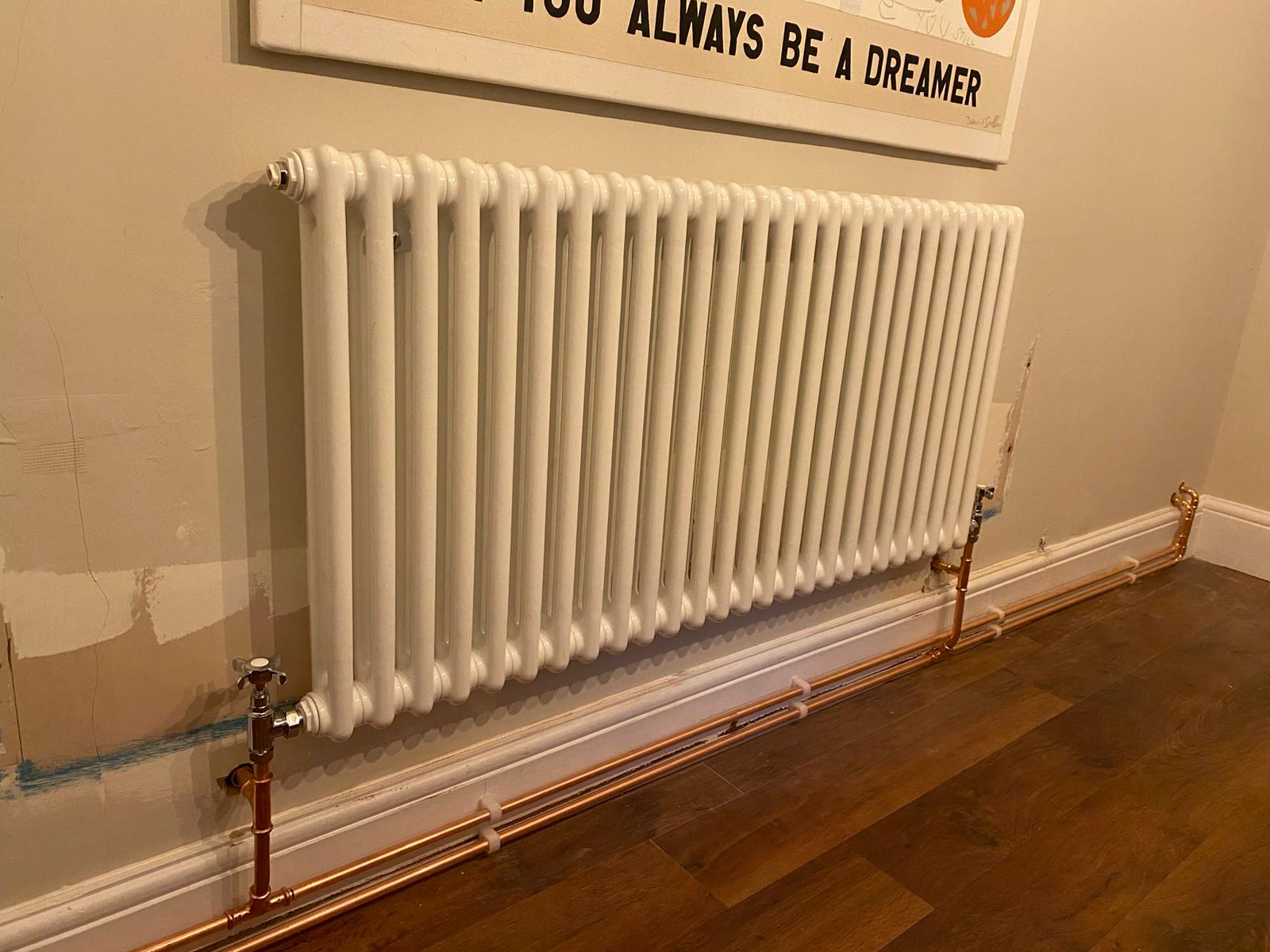White column radiator installed with copper pipework and chrome valves