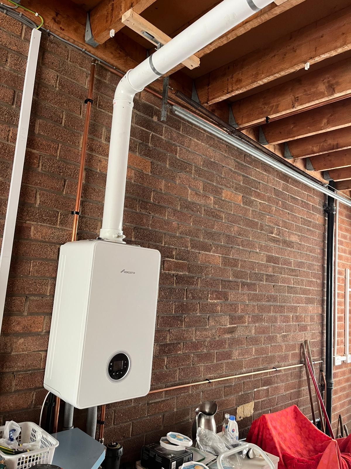 Worcester Bosch boiler mounted on brick garage wall with flue system